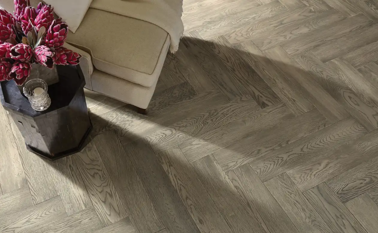 Herringbone hardwood floor closeup with chair and side table.